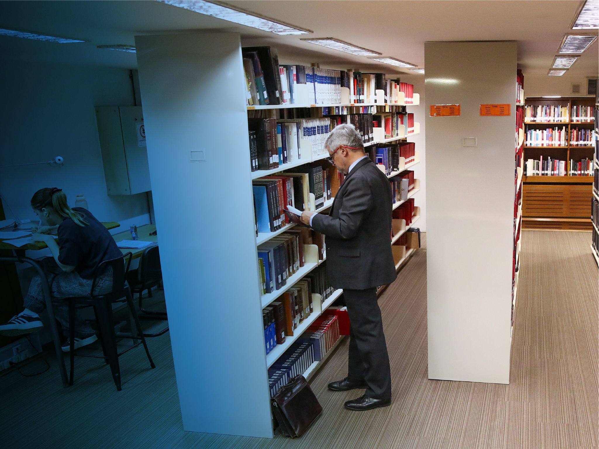 Fotografía de un profesor mirando libros en la biblioteca
